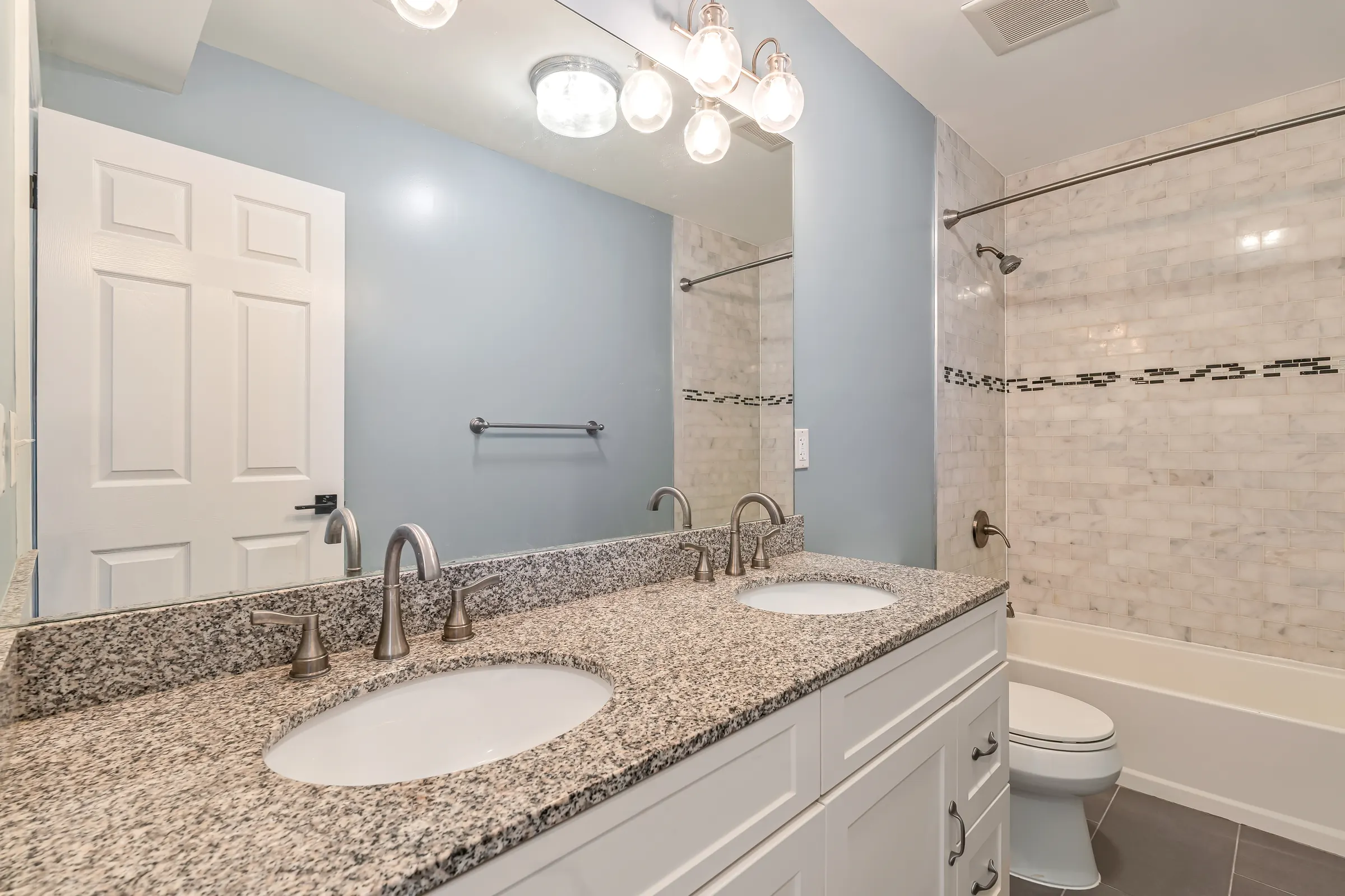 Primary bathroom with a double vanity, granite counter, and tub at Apartment B, 829 Garden Street.