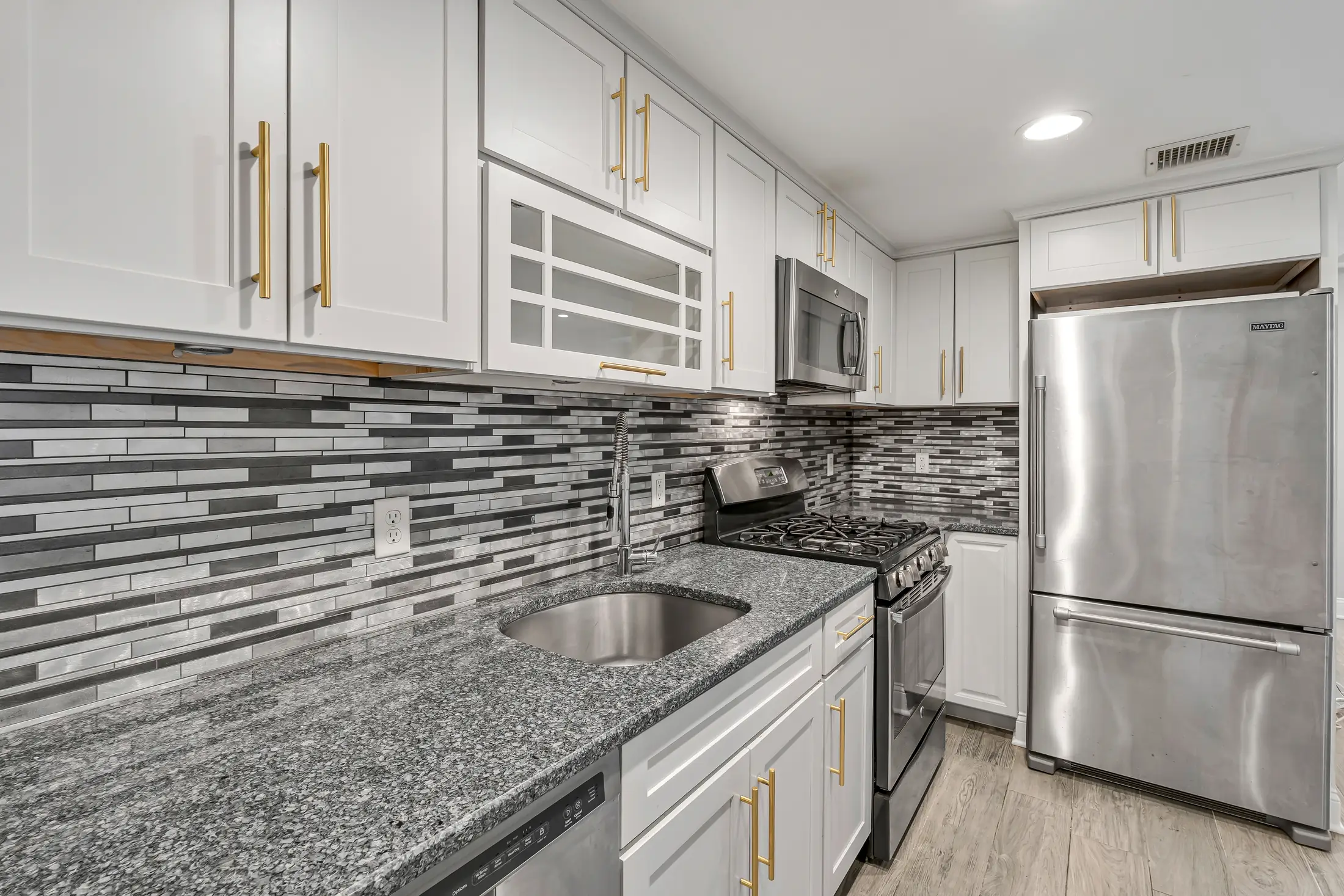 Granite counters, stainless sink, gas range, and refrigerator in the kitchen at 829 Garden Street.