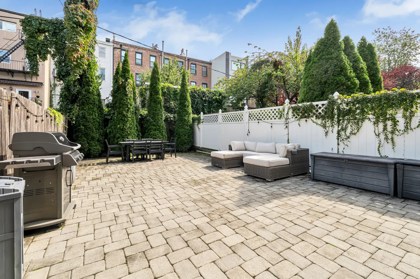 Private paver patio with a white fence and trees at Apartment B, 829 Garden Street, Uptown Hoboken.