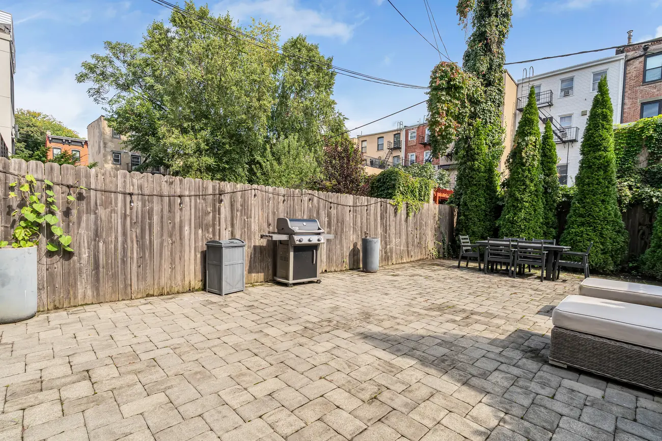 Paver patio along a wood fence with trees at the garden apartment, 829 Garden Street.