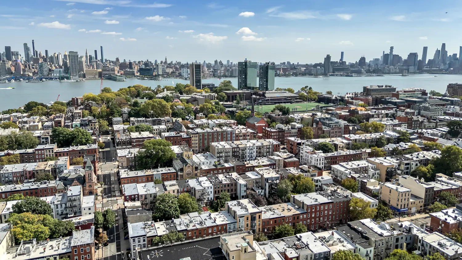 Wide aerial view of Hoboken, the Hudson River, and the Manhattan skyline above the patio at 829 Garden Street.